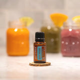 dōTERRA DDR Prime 15ml – Flasche auf Holzuntergrund umgeben von Orangen, grünen und roten Säften | doTERRA