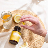 dōTERRA EO Mega Softgels – Softgel in der Hand mit Zitrone und Wassergefäß auf Korbgeflecht-Tablett | doTERRA