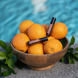 dōTERRA Neroli Touch Roll-on 10ml mit Orangenschüssel auf Holz neben blauem Pool | doTERRA