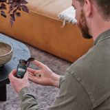 dōTERRA PB Restore – Bärtiger Mann auf Ledersofa mit Flasche und Kapseln | doTERRA