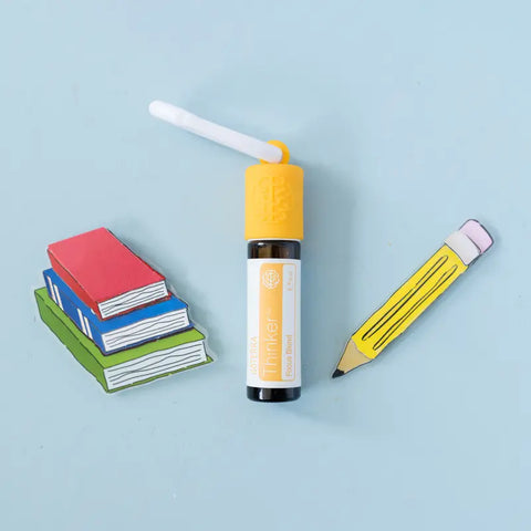 dōTERRA Thinker Roll-On 10ml mit Büchern und Stift vor blauem Hintergrund | doTERRA
