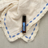 dōTERRA ZenGest Touch Roll-On 10ml auf weißer Decke mit Fransen, bestickt, blau | doTERRA